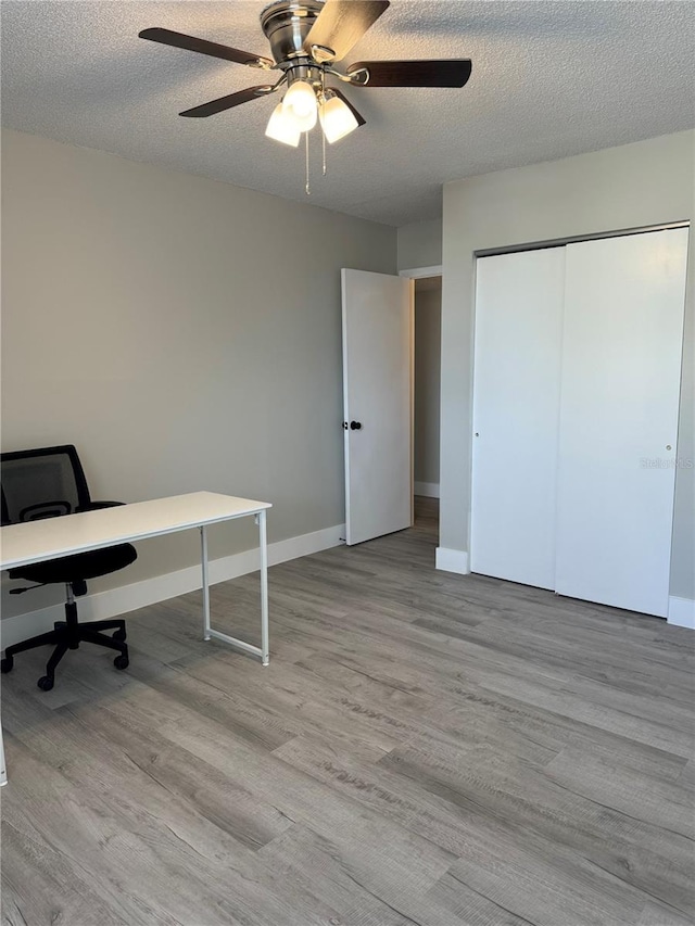 office area featuring ceiling fan, baseboards, a textured ceiling, and wood finished floors