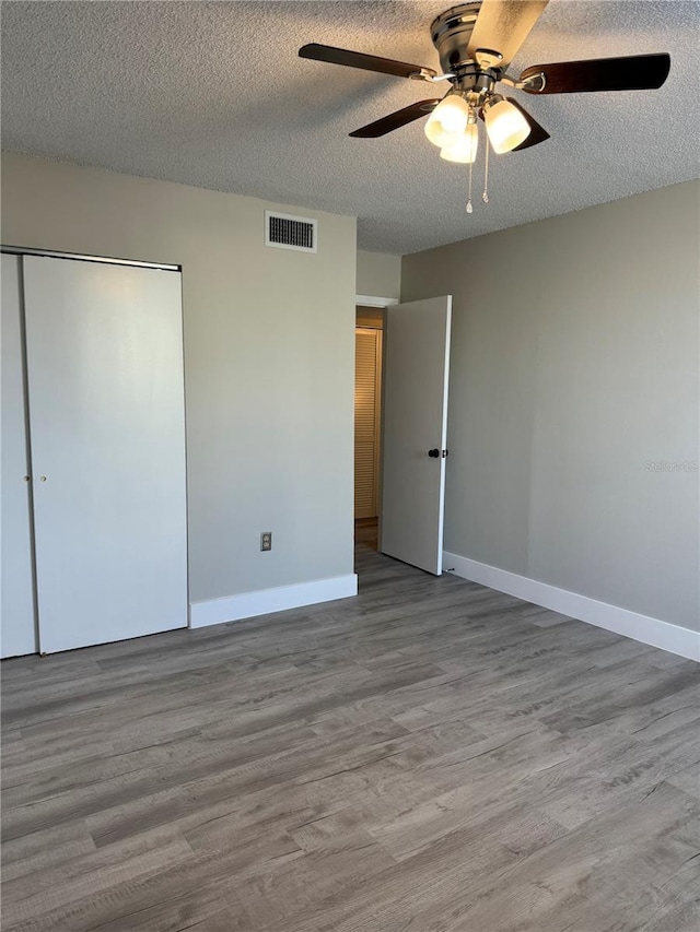 unfurnished bedroom with wood finished floors, visible vents, and baseboards