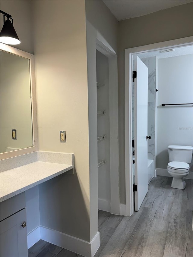 bathroom with visible vents, baseboards, toilet, wood finished floors, and vanity