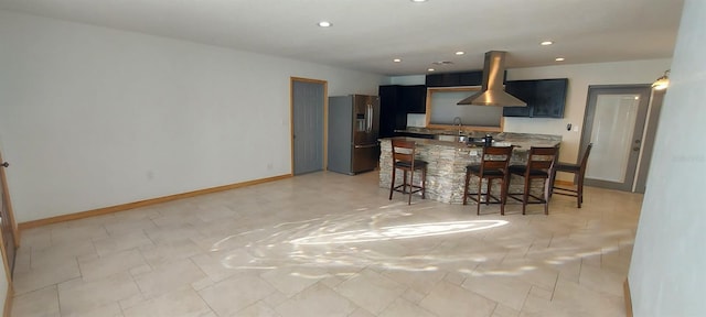 kitchen featuring a kitchen breakfast bar, stainless steel refrigerator with ice dispenser, sink, and island range hood