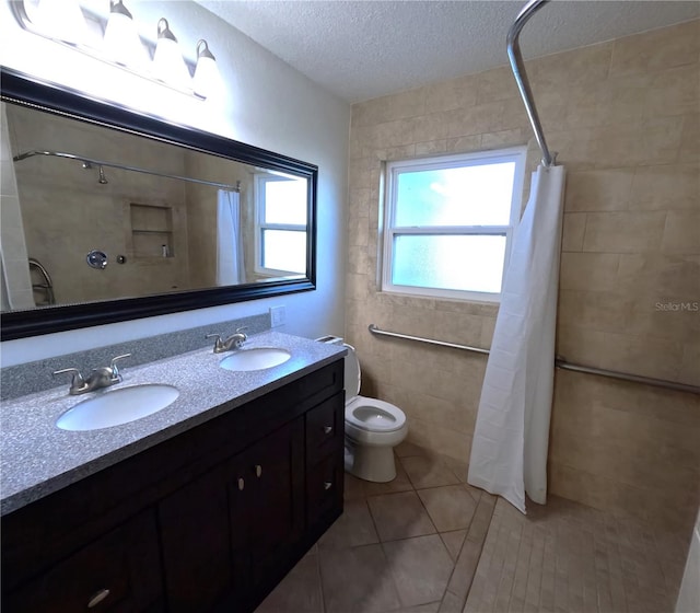 bathroom featuring toilet, a shower with shower curtain, tile walls, vanity, and a textured ceiling