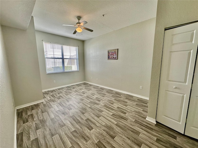 empty room featuring hardwood / wood-style flooring, ceiling fan, and a textured ceiling