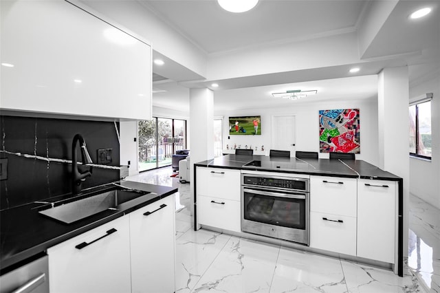 kitchen featuring ornamental molding, marble finish floor, stainless steel oven, and a sink