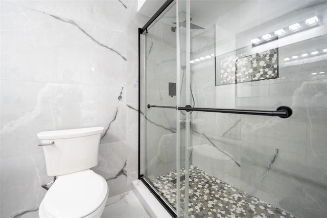 bathroom with marble finish floor, toilet, tile walls, and a marble finish shower