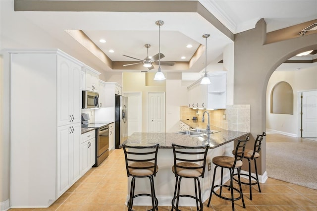 kitchen featuring kitchen peninsula, a tray ceiling, light tile patterned flooring, white cabinetry, and appliances with stainless steel finishes