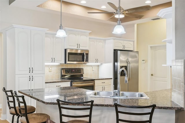 kitchen featuring appliances with stainless steel finishes, kitchen peninsula, white cabinets, and a breakfast bar area