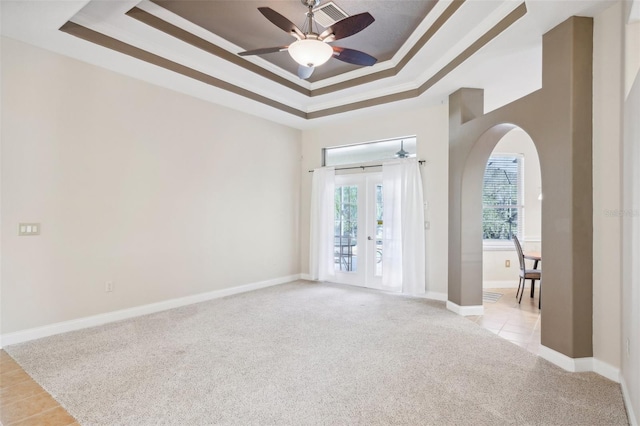 carpeted empty room featuring french doors, ornamental molding, ceiling fan, and a raised ceiling