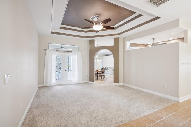 spare room with french doors, a raised ceiling, ceiling fan, crown molding, and light colored carpet