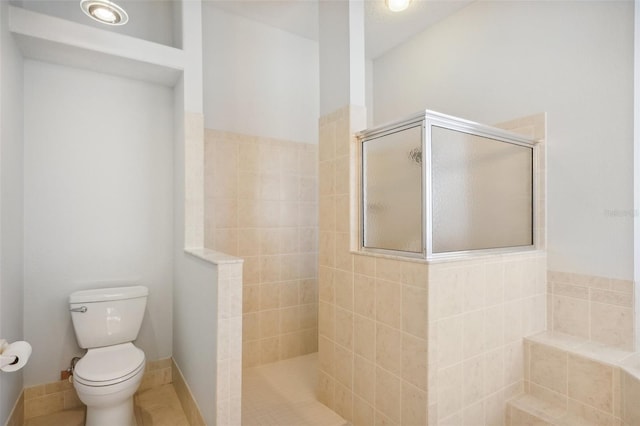 bathroom featuring toilet, tile patterned floors, and tiled shower