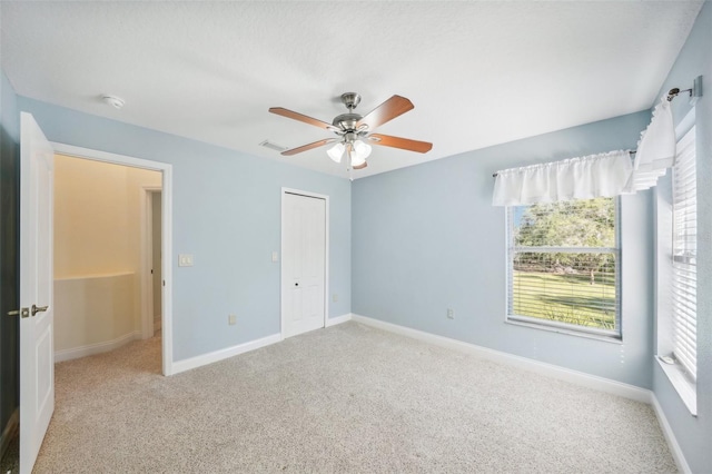 unfurnished bedroom with light colored carpet, a closet, and ceiling fan