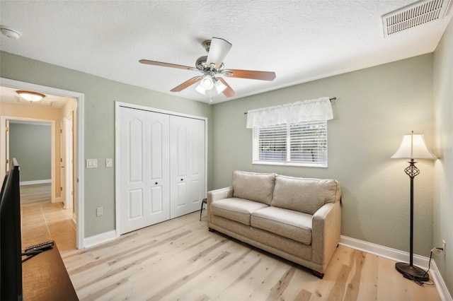 sitting room featuring a textured ceiling, light hardwood / wood-style floors, and ceiling fan