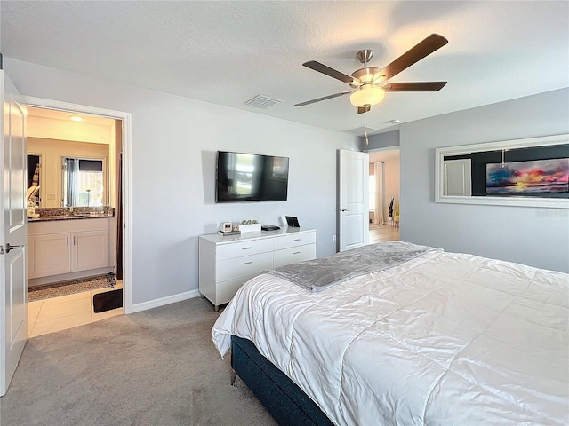 bedroom featuring a textured ceiling, ceiling fan, light colored carpet, and ensuite bathroom