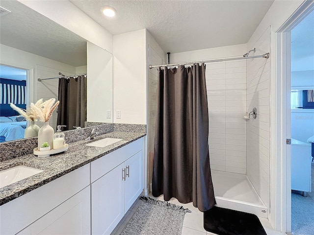 bathroom with tile patterned floors, vanity, a textured ceiling, and walk in shower