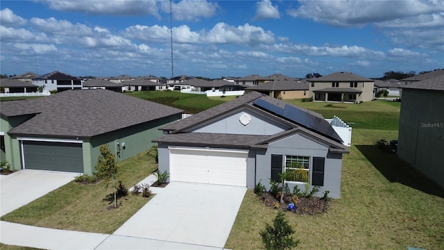 ranch-style house featuring solar panels, a garage, and a front lawn