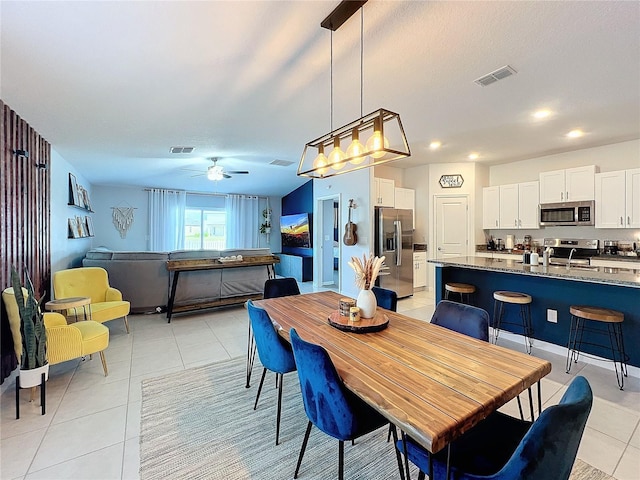 tiled dining area with ceiling fan and sink