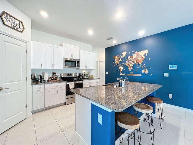 kitchen featuring white cabinetry, a kitchen island with sink, sink, and appliances with stainless steel finishes