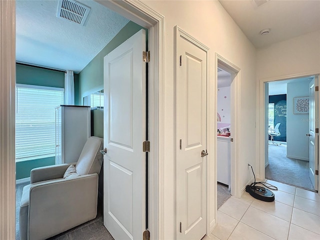 hallway with a healthy amount of sunlight, light tile patterned flooring, and a textured ceiling