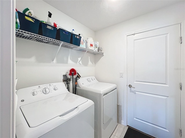 clothes washing area featuring washing machine and dryer, light tile patterned floors, and a textured ceiling