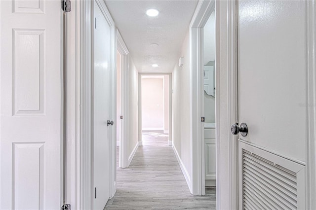 hall featuring a textured ceiling and light hardwood / wood-style flooring