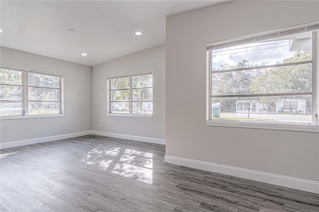 spare room featuring dark hardwood / wood-style flooring, lofted ceiling, and a textured ceiling