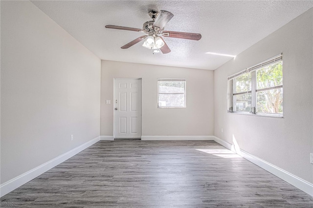 empty room with hardwood / wood-style floors, ceiling fan, a textured ceiling, and vaulted ceiling