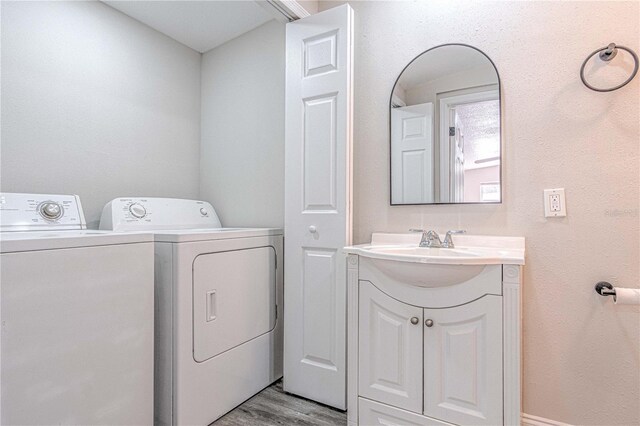 laundry room with washing machine and clothes dryer and light wood-type flooring