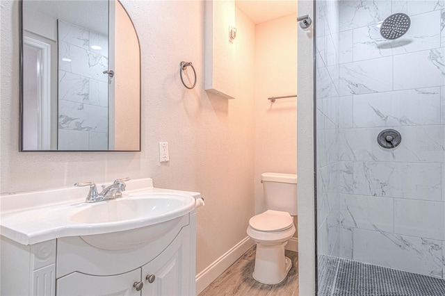 bathroom featuring toilet, vanity, hardwood / wood-style floors, and a tile shower