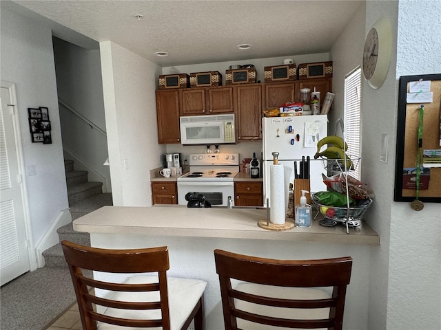 kitchen featuring kitchen peninsula, a breakfast bar, and white appliances