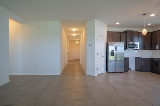 kitchen featuring stainless steel appliances, dark brown cabinets, light tile patterned floors, and decorative light fixtures