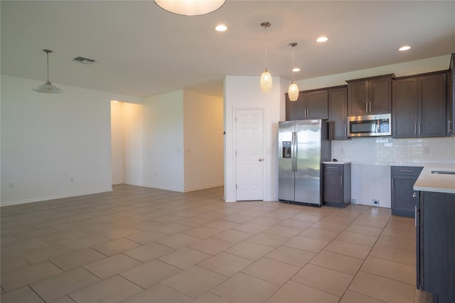 kitchen featuring appliances with stainless steel finishes, hanging light fixtures, dark brown cabinets, and backsplash