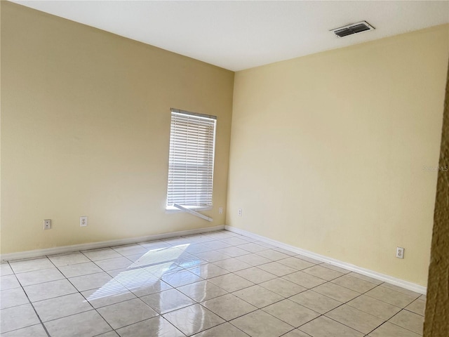 empty room with baseboards, visible vents, and light tile patterned flooring