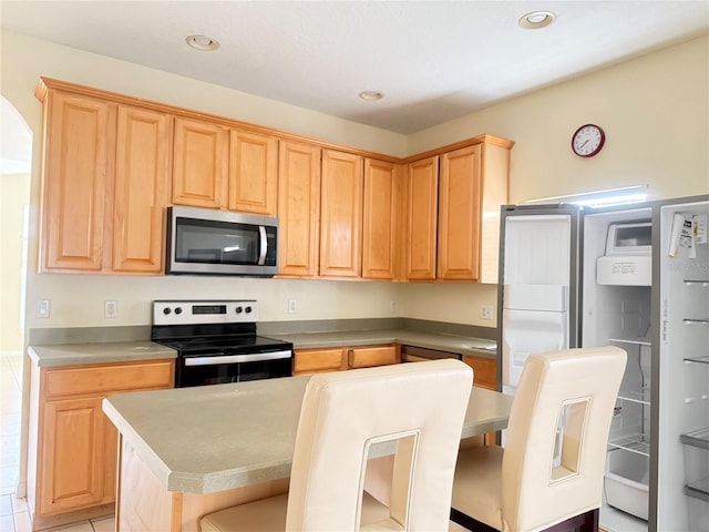 kitchen featuring stainless steel appliances, a center island, light countertops, and recessed lighting