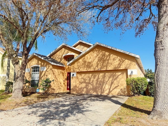 ranch-style home featuring concrete driveway, an attached garage, and stucco siding