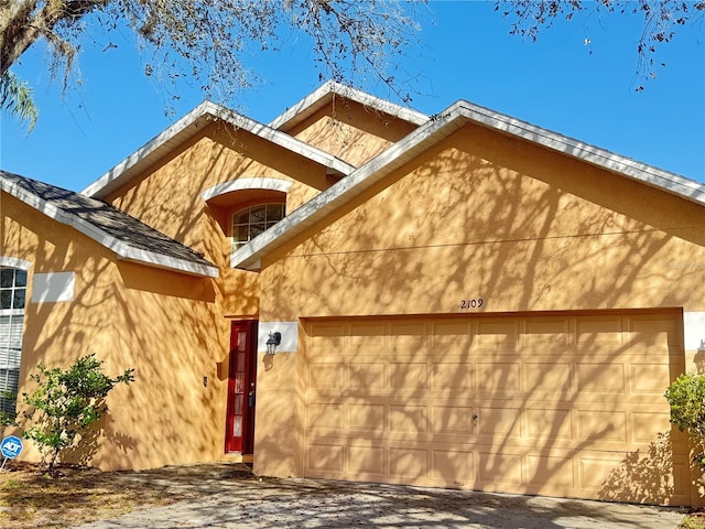 view of side of home with driveway, an attached garage, and stucco siding