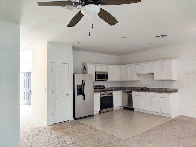 114 Mandovi St, Davenport, FL 33837 - kitchen featuring stainless steel appliances, light colored carpet, dark countertops, a sink, and white cabinets