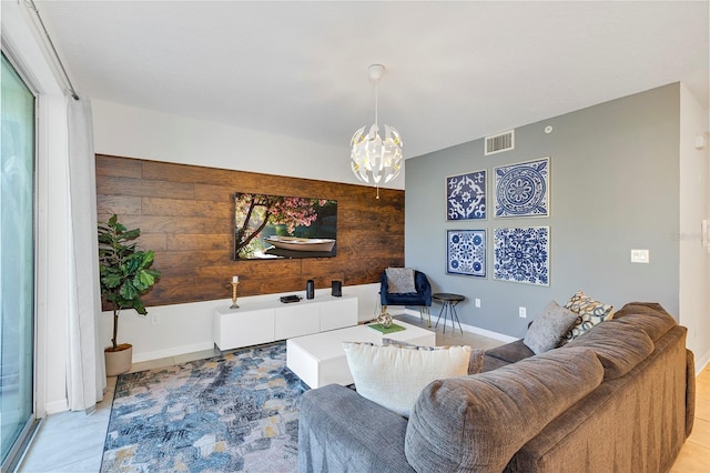 tiled living room featuring wood walls and a chandelier