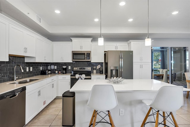 kitchen featuring sink, decorative light fixtures, stainless steel appliances, and a kitchen island