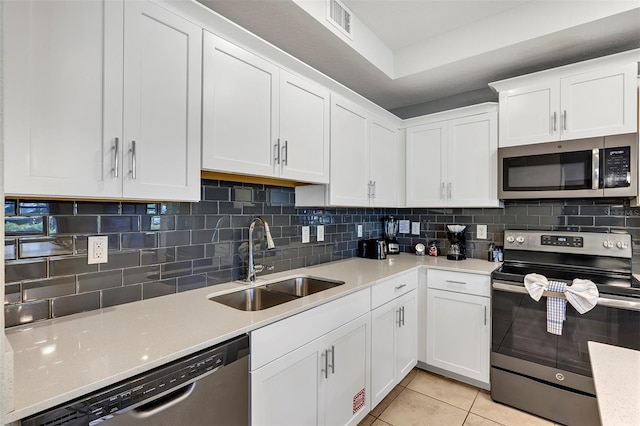 kitchen with tasteful backsplash, light tile patterned floors, white cabinetry, sink, and stainless steel appliances