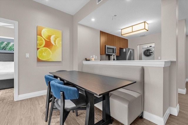 dining space featuring stacked washer and dryer and light hardwood / wood-style floors