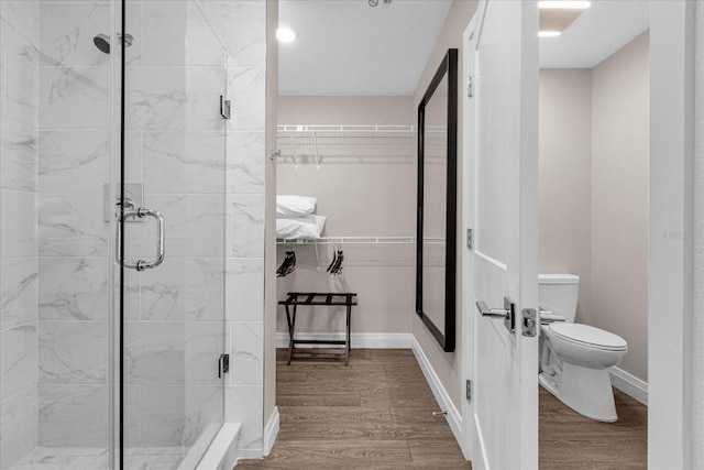 bathroom with toilet, a shower with shower door, and wood-type flooring