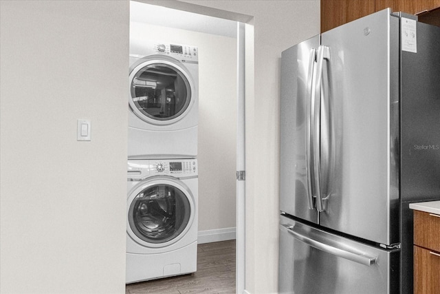 laundry room featuring light hardwood / wood-style floors and stacked washing maching and dryer