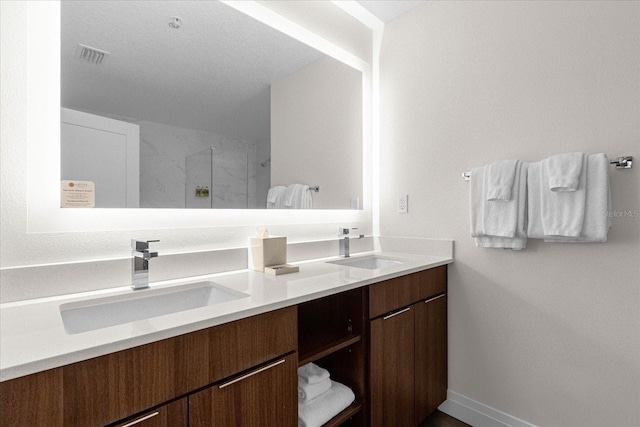 bathroom with vanity, a textured ceiling, and walk in shower