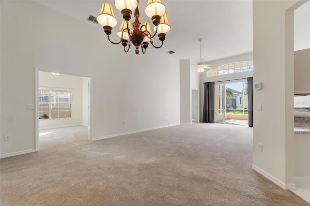 unfurnished room with a towering ceiling, light colored carpet, ceiling fan with notable chandelier, and plenty of natural light