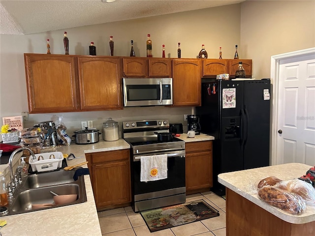 kitchen featuring lofted ceiling, stainless steel appliances, sink, light tile patterned floors, and a textured ceiling