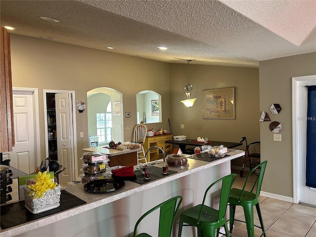 kitchen featuring hanging light fixtures, a textured ceiling, and light tile patterned floors