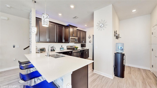 kitchen with kitchen peninsula, a kitchen bar, sink, pendant lighting, and stainless steel appliances