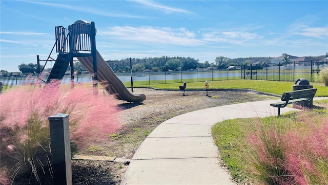 view of playground with a yard and a water view