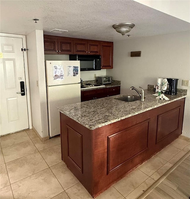 kitchen featuring light stone counters, stainless steel gas stovetop, a textured ceiling, sink, and white refrigerator