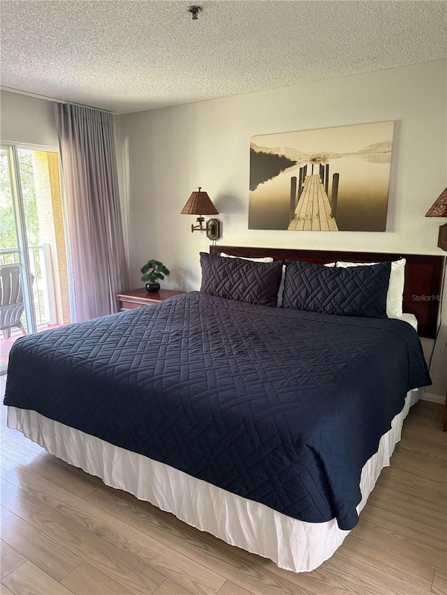 bedroom with a textured ceiling, hardwood / wood-style flooring, and access to outside