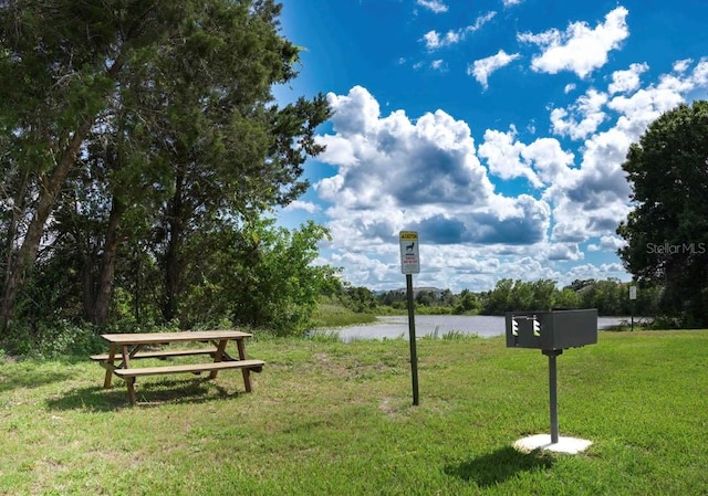 view of home's community featuring a lawn and a water view